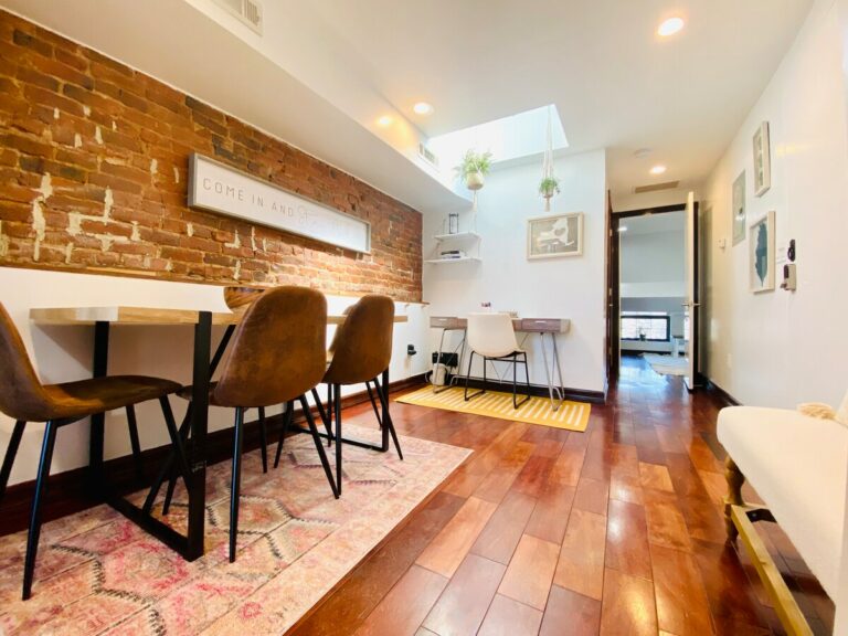 Inviting dining space with wooden table, exposed brick wall, and skylight in a cozy brownstone suite in Bed-Stuy, Brooklyn.