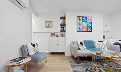 Well-organized living room with gray sofa, glass coffee table, built-in shelves, and integrated washer/dryer.